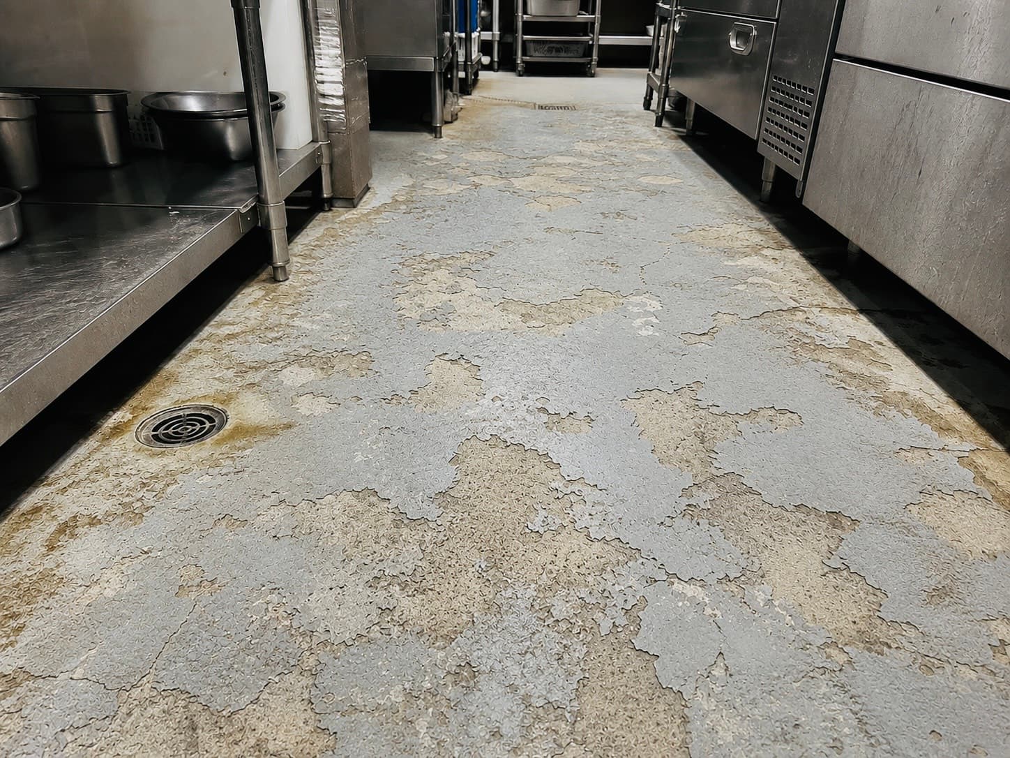 業務用厨房の通路で塗膜が剥がれ床材が露出している状態(施工前)